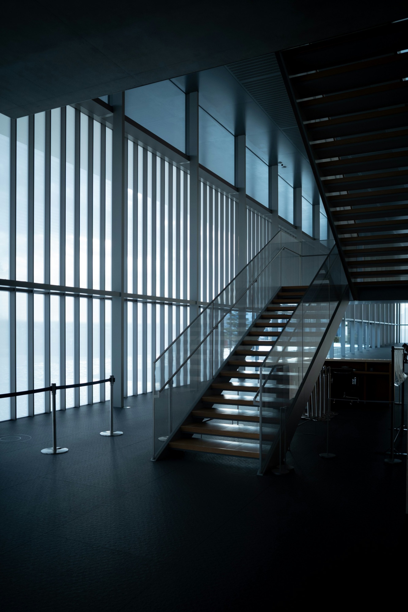 Multi-story commercial stair with glass railings and metal handrails