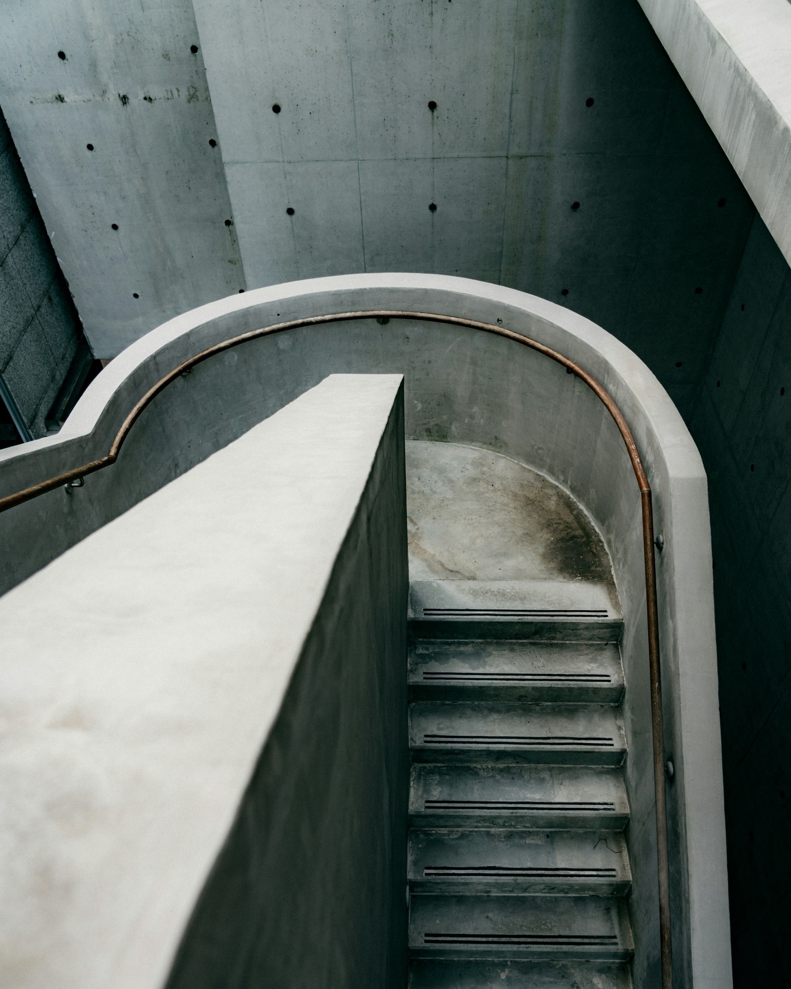 Curved concrete stair with continuous metal handrail