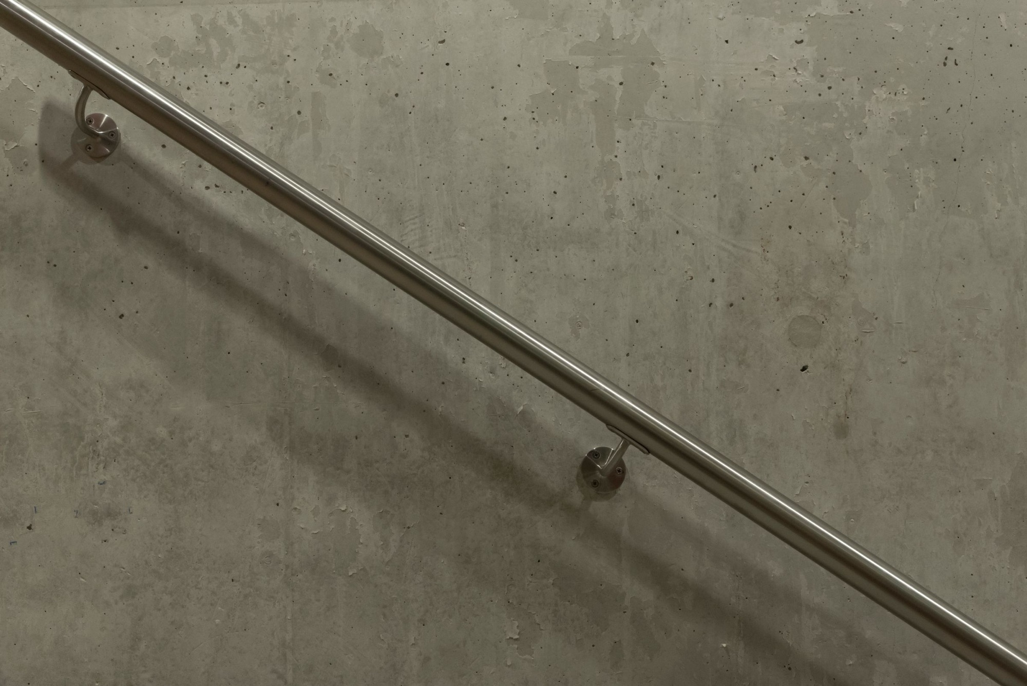Stainless steel handrail mounted on a concrete stair wall