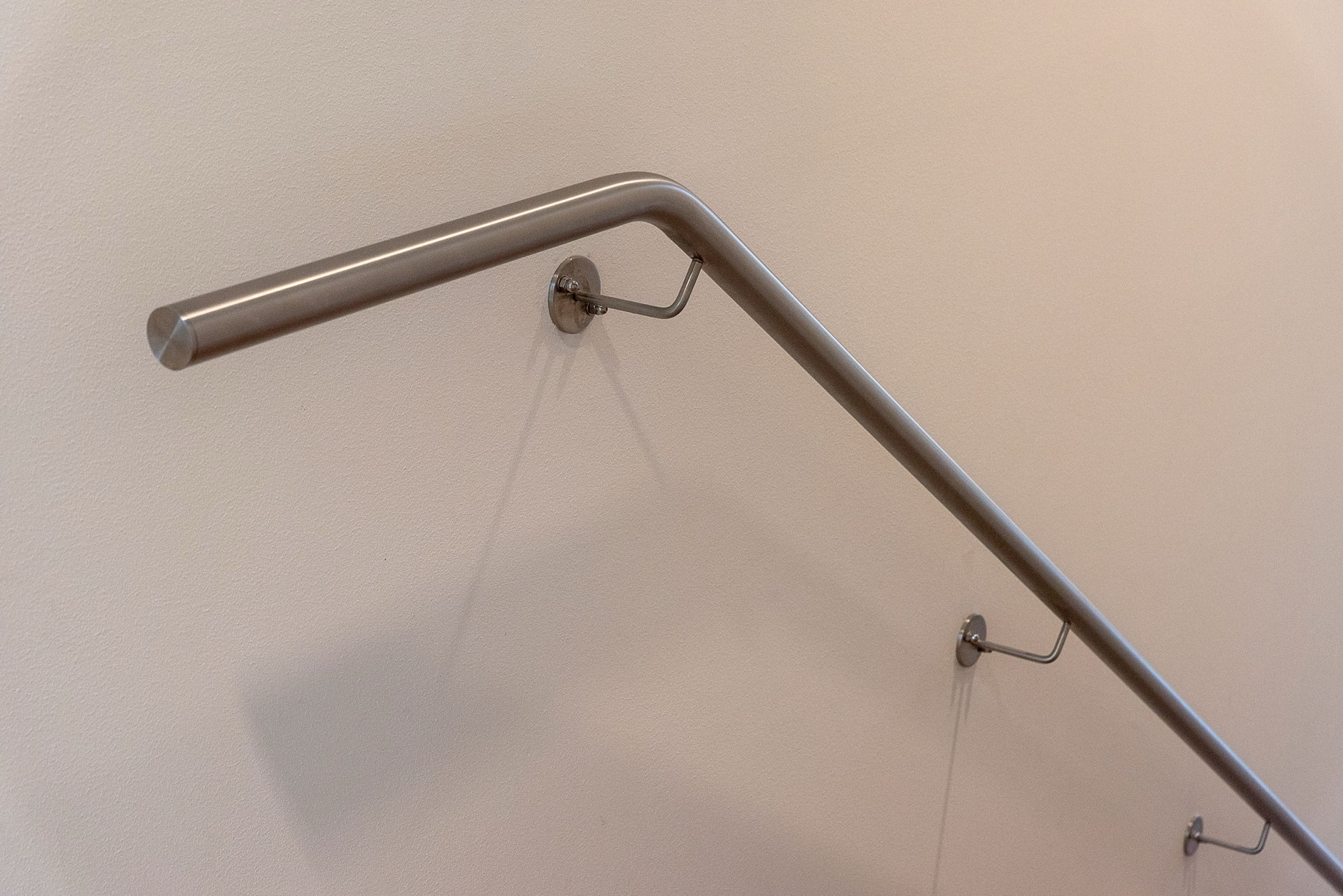 Wall-mounted stainless steel handrail along a stair